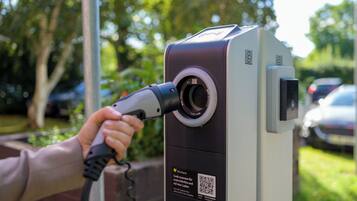 Parquímetro com código QR e instruções para escanear um código para o primeiro passo do estacionamento e carregamento ad-hoc.