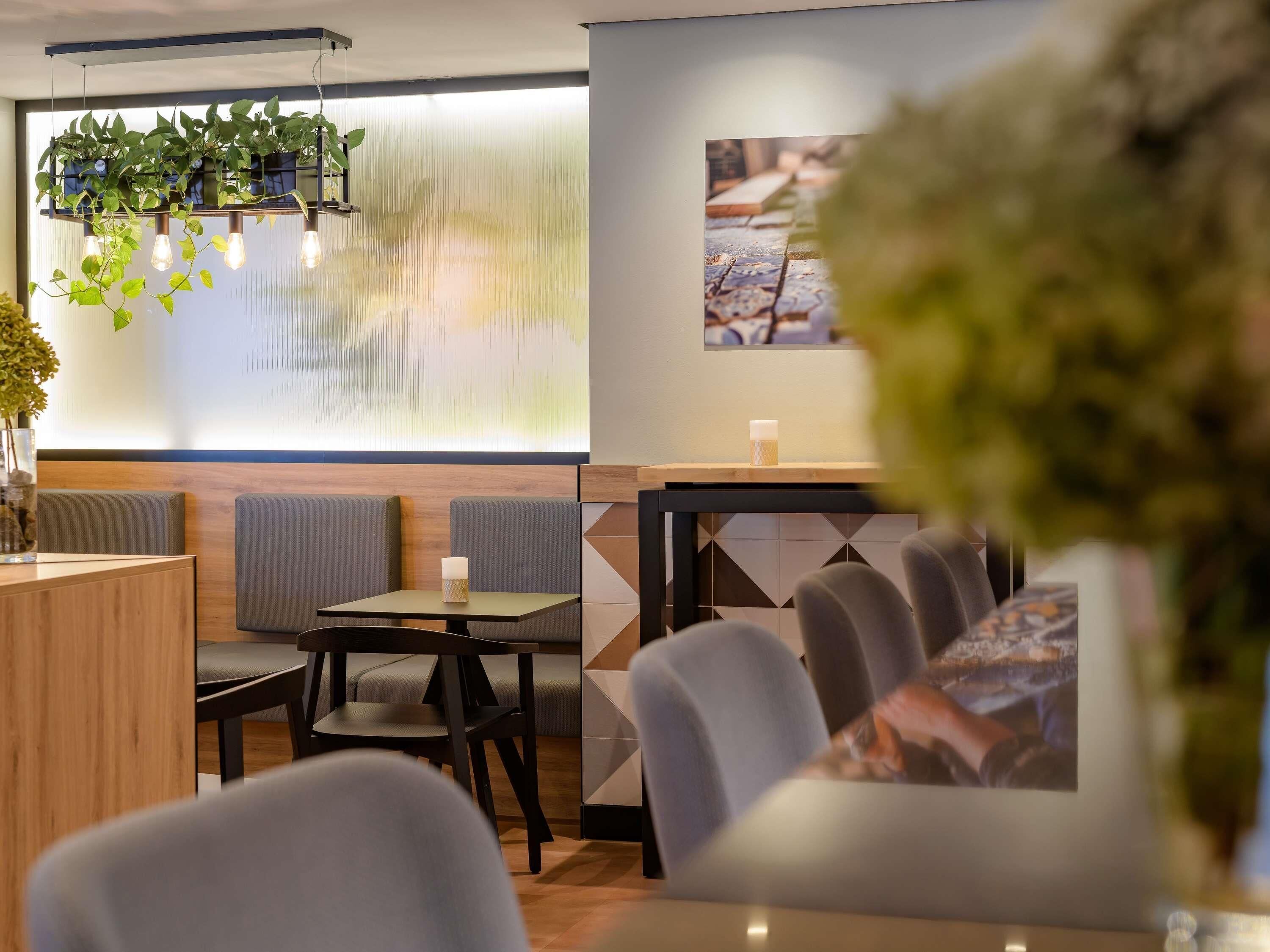 A modern restaurant interior with a bar area, seating, and a large window with a view.