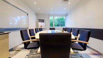 A conference room with a round table, chairs, a projector, and a whiteboard.