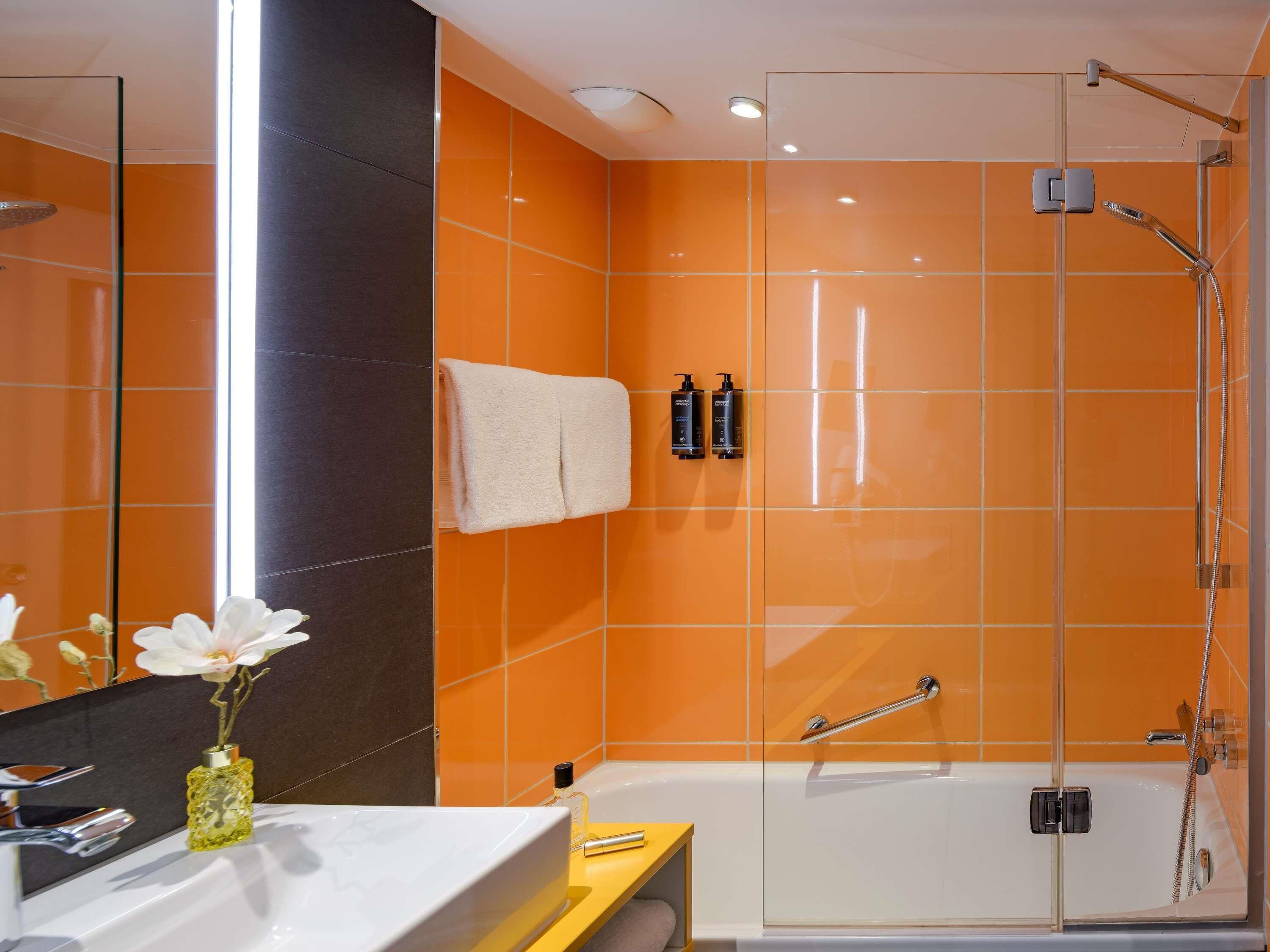 A modern bathroom with a glass-enclosed shower, a white bathtub, and a large mirror.