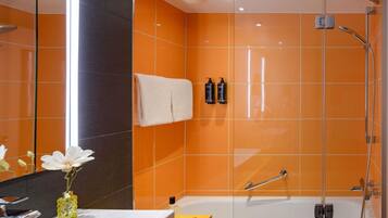 A modern bathroom with a glass-enclosed shower, a white bathtub, and a large mirror.