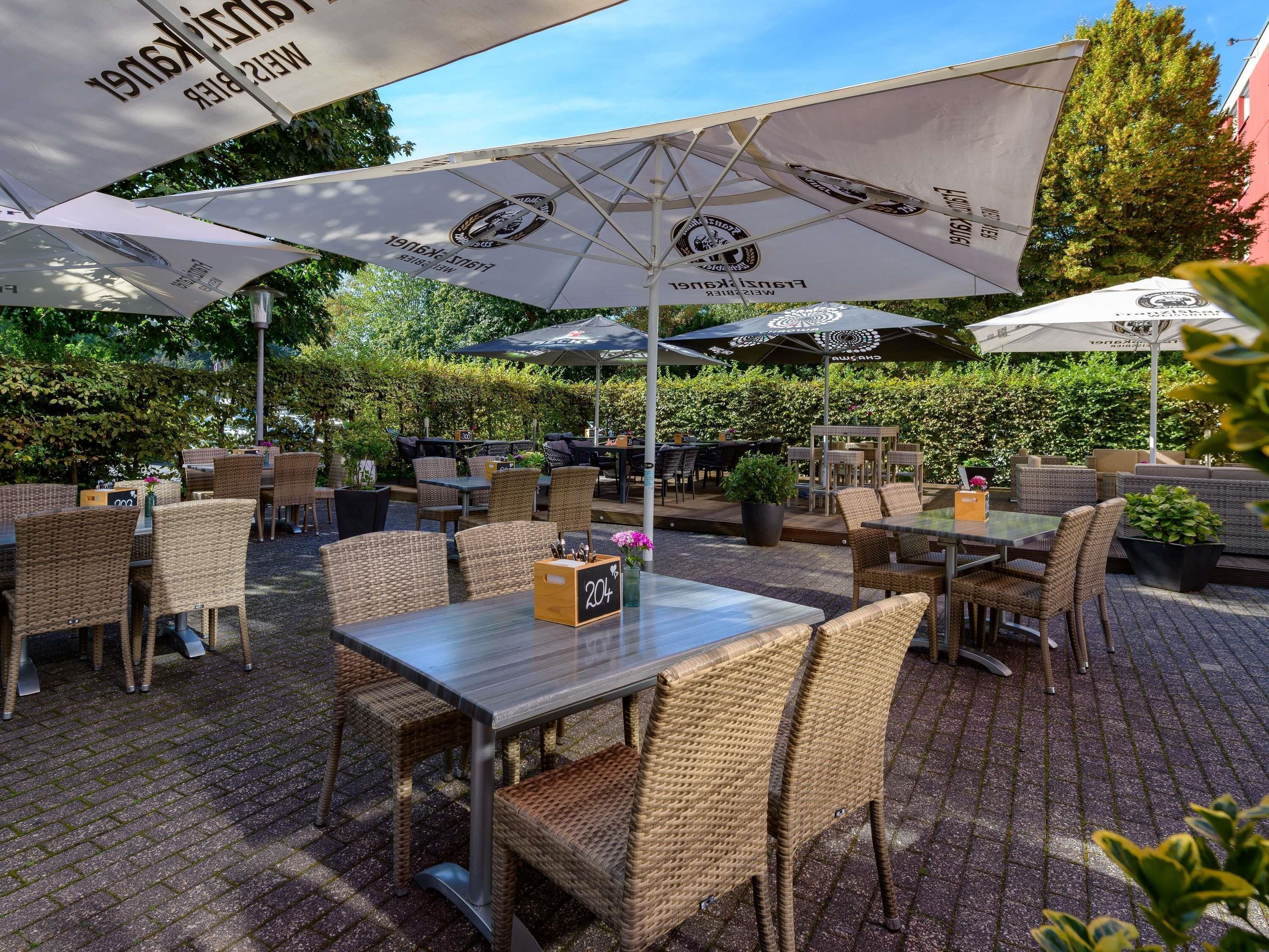 Un espace extérieur aménagé avec des meubles en osier, des tables et des parasols.