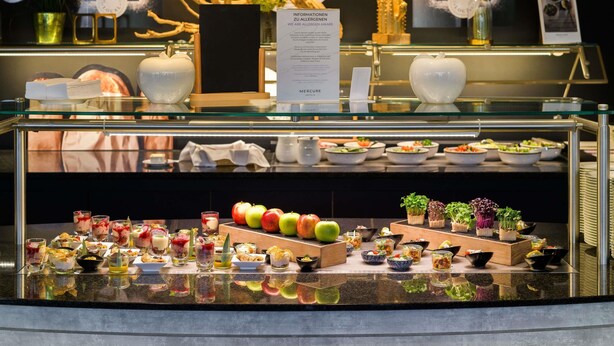 A buffet area with various food items and a menu sign. - Mercure Hotel Köln West (Cologne)