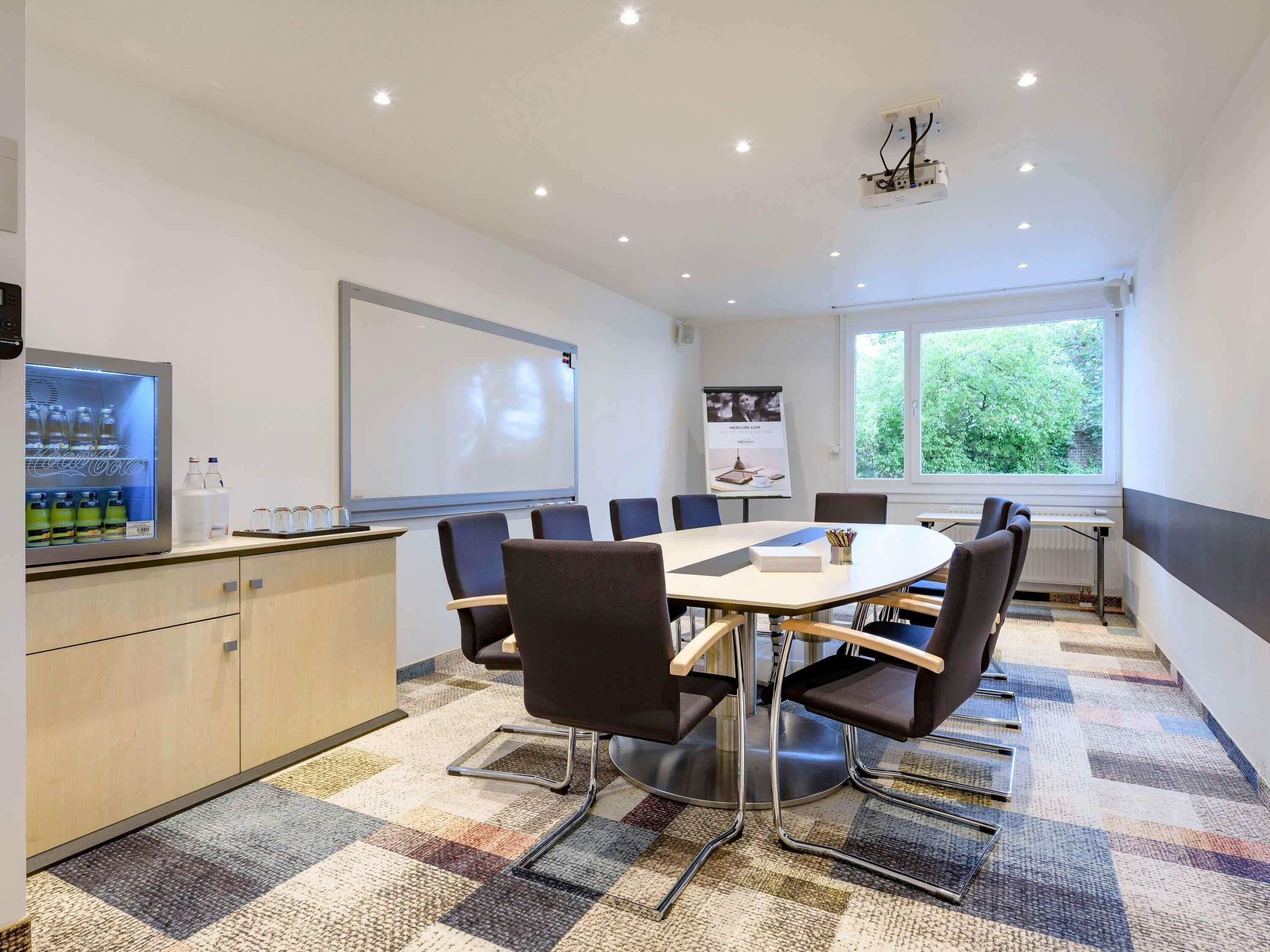 A conference room with a whiteboard, projector, and a Coca-Cola refrigerator.