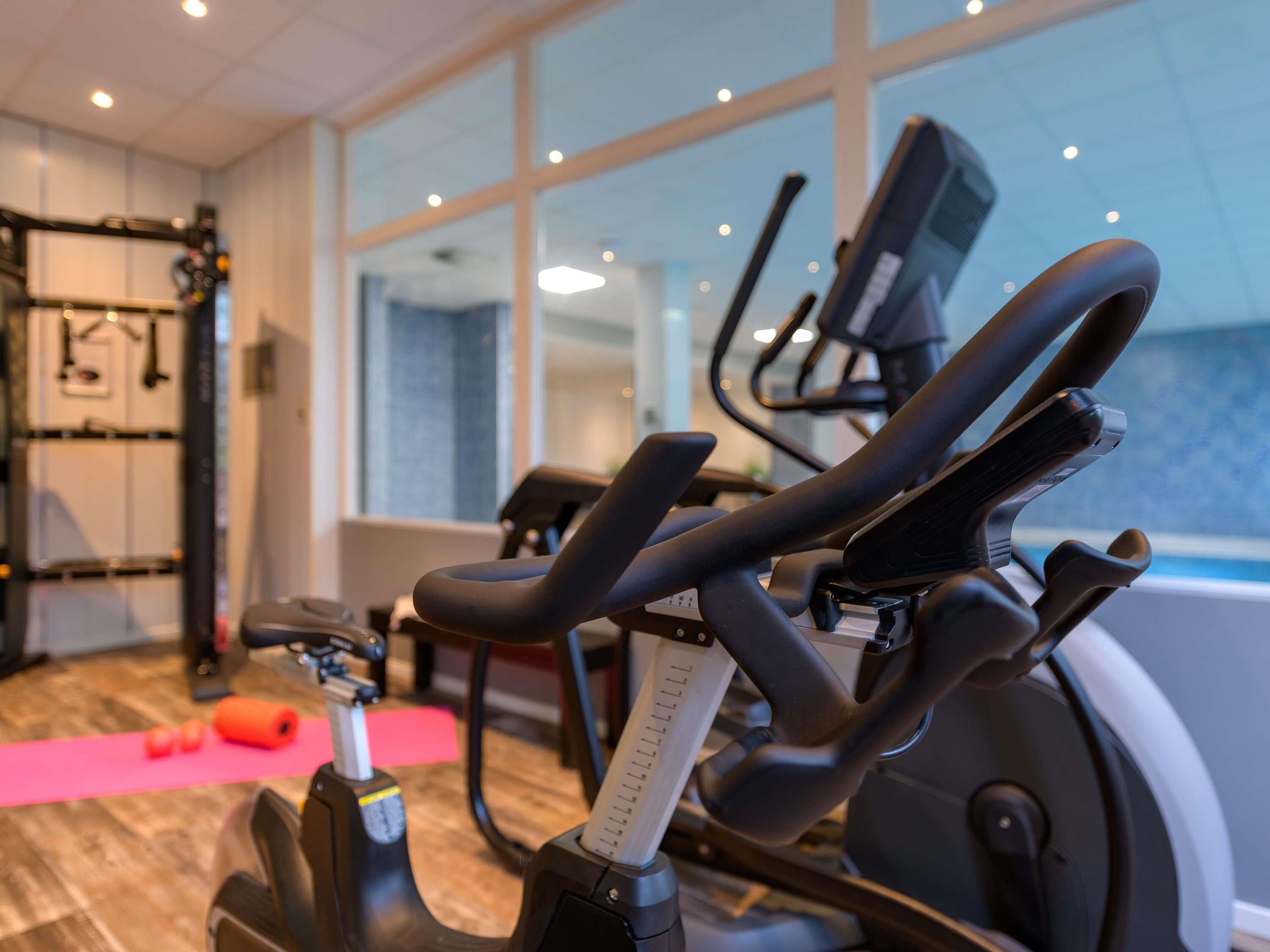 A gym with exercise equipment, a yoga mat, and a window with a view.
