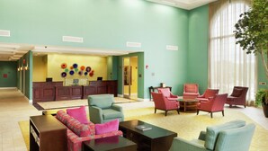 A lobby with teal walls, a reception desk, and multiple seating areas with armchairs and sofas. - DoubleTree by Hilton Greensboro (Greensboro)