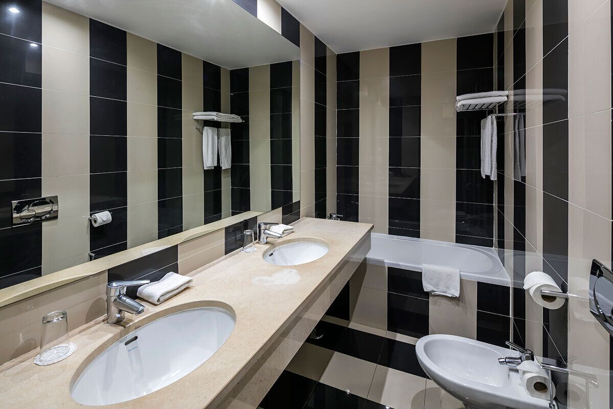 Une salle de bain moderne avec deux lavabos, un grand miroir et une baignoire.