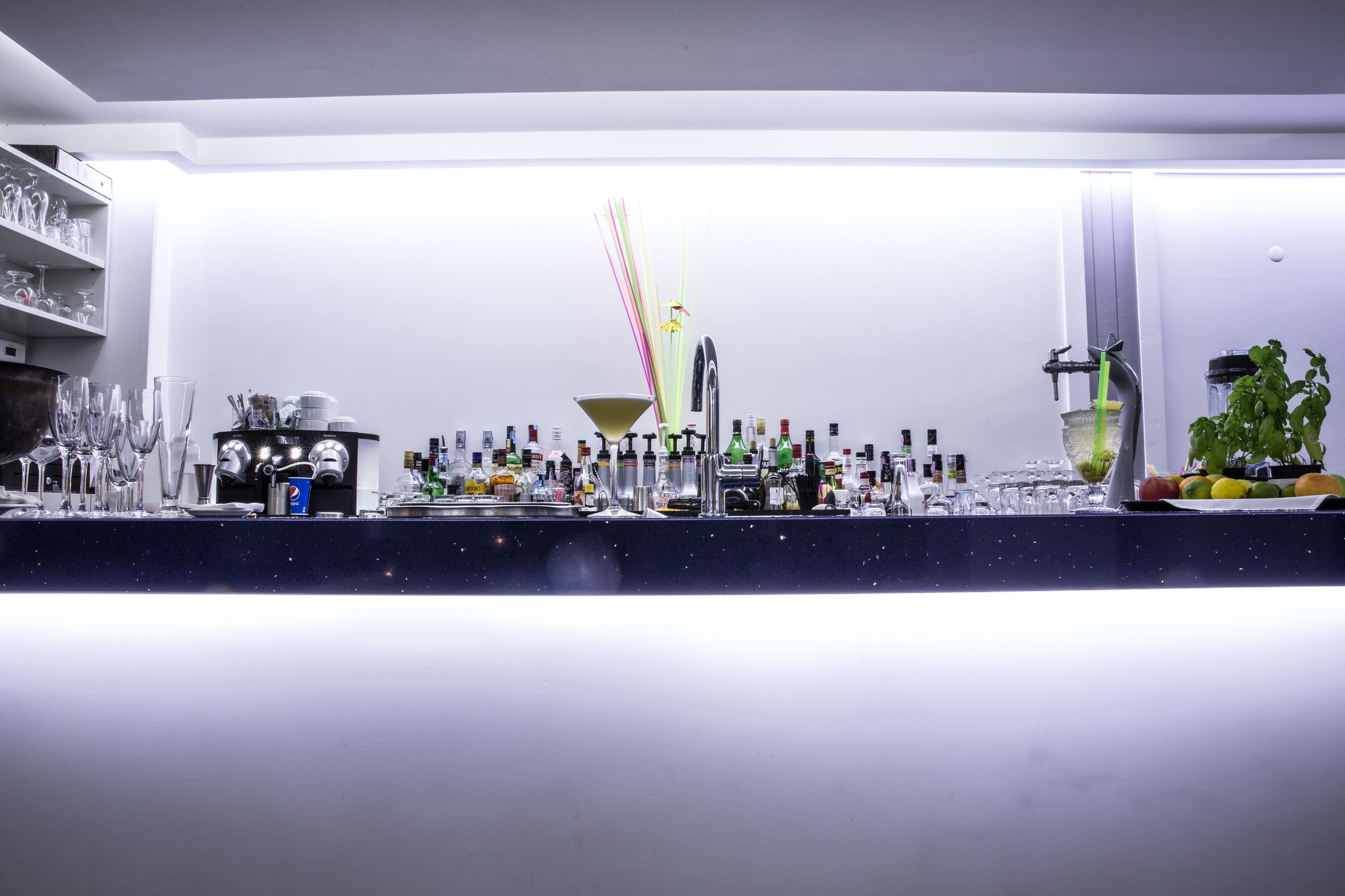 A bar area with various bottles, glasses, and a decorative plant.