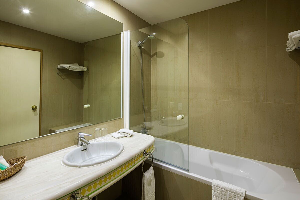 Un baño con lavamanos, espejo, ducha y bañera.