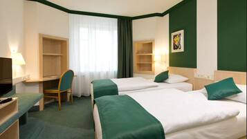 A hotel room with two beds, a desk, a chair, and a TV.