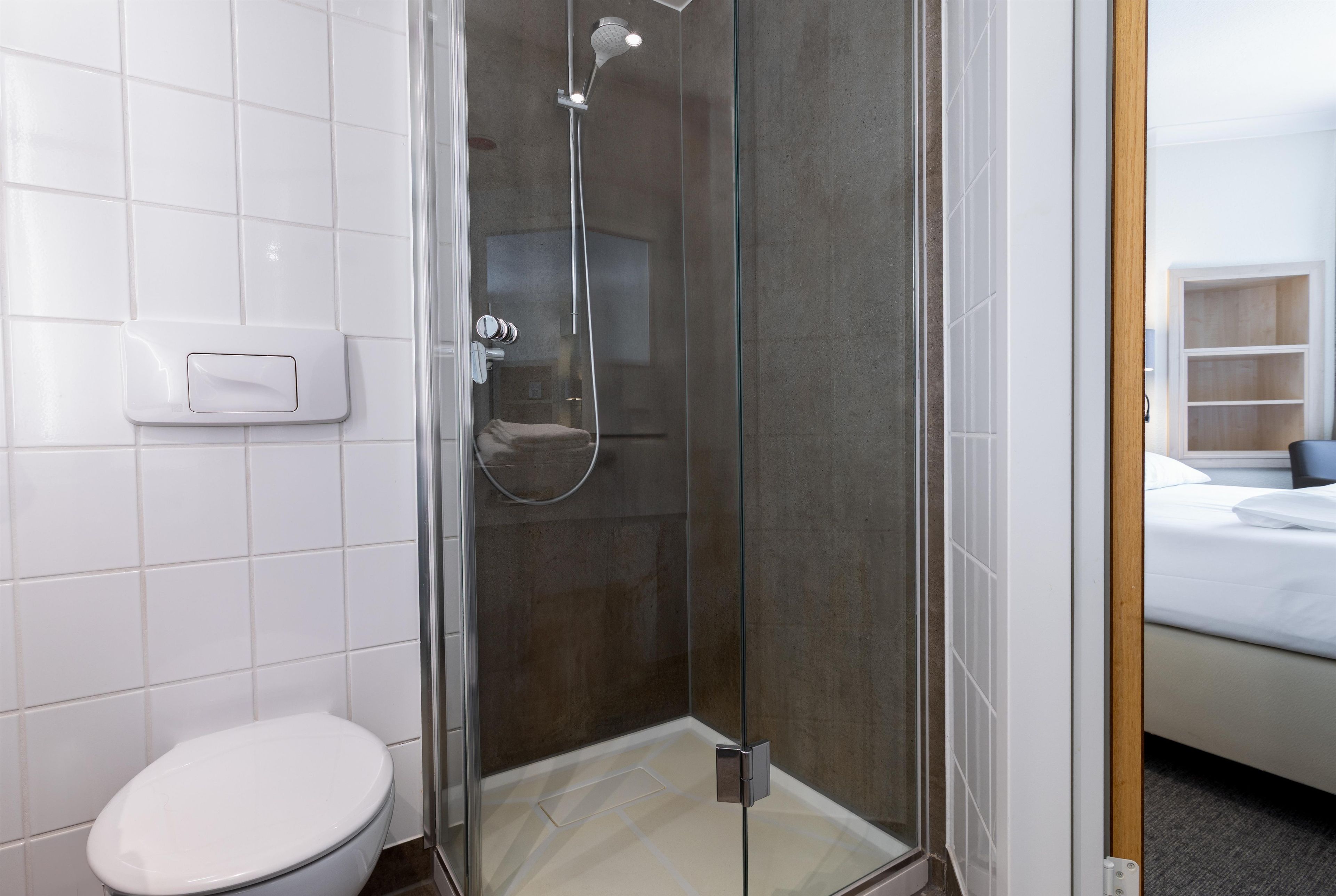 Une salle de bain moderne avec une douche à parois de verre, des toilettes et un lavabo blanc.
