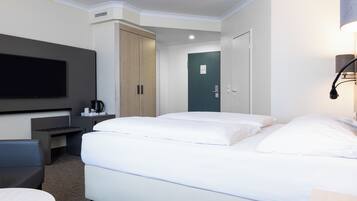 Una habitación de hotel con una cama, un escritorio, un televisor y una puerta.
