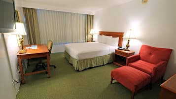 A hotel room with a bed, desk, chair, and two bedside lamps.