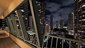 Een nachtelijke stadsgezicht met hoge gebouwen, een brug met groene leuningen en een betegelde vloer.