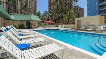 Una piscina al aire libre, sillones reclinables de piscina