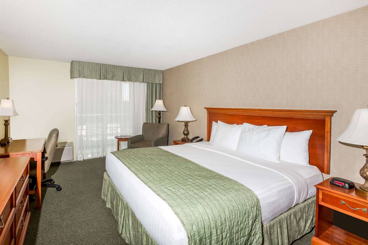 Een hotelkamer met een groot bed, een bureau met stoel, een lamp en een telefoon.