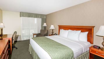 Een hotelkamer met een groot bed, een bureau met stoel, een lamp en een telefoon.