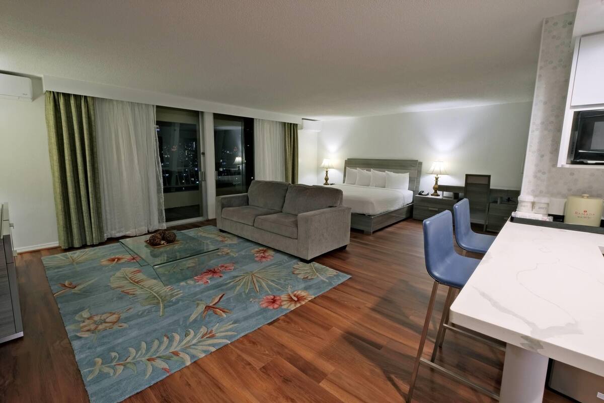Een hotelkamer met een bank, een bed, een eettafel en een televisie.