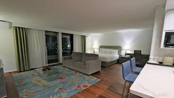 Habitación de hotel con sofá, cama, mesa de comedor y televisor.