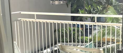 A balcony with white metal railings, a white plastic chair, and a small round table.