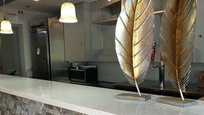 Een receptiezone met een stenen muur, een balie en twee decoratieve gouden bladeren.