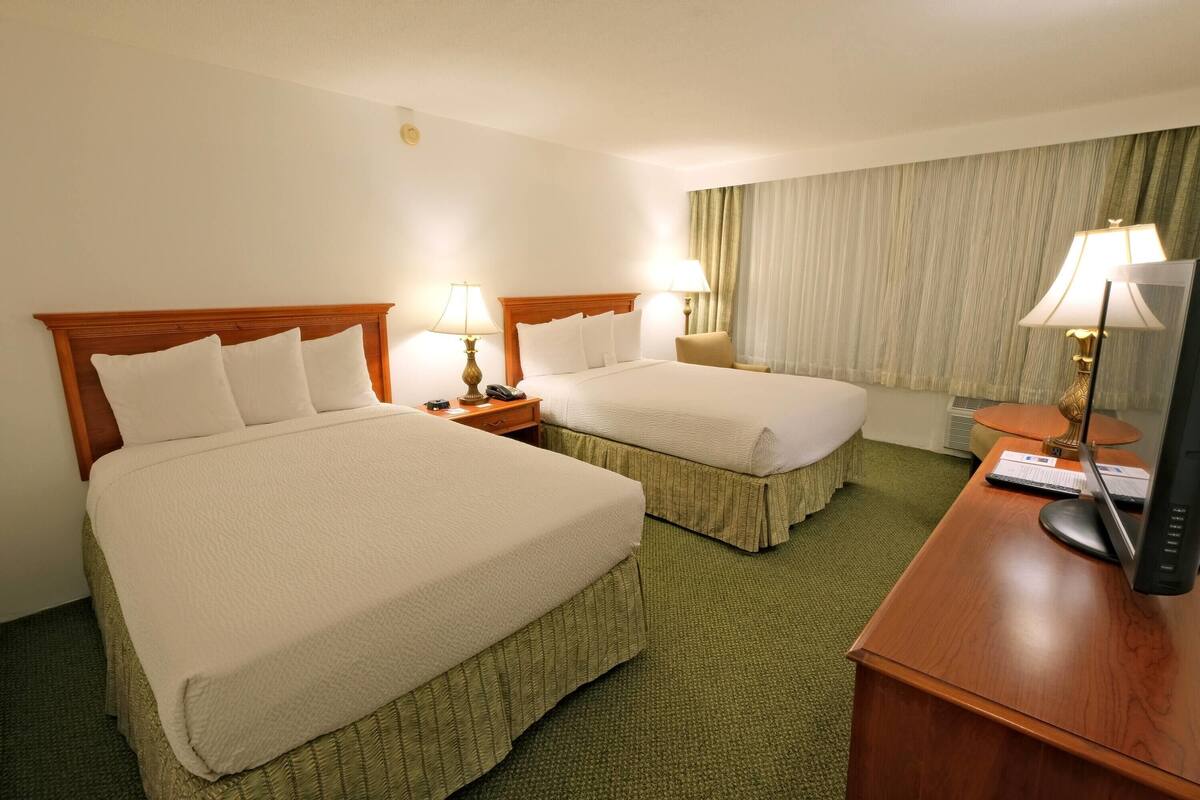 Een hotelkamer met twee bedden, een bureau met een computer en een stoel.