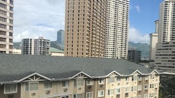 A multi-story residential building with a flat roof and a balcony on the ground floor.