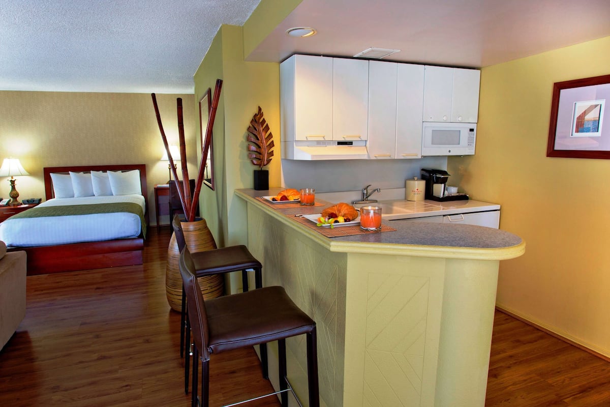 Een hotelkamer met een bed, een kleine kitchenette, een ontbijtbalk en een zithoek.