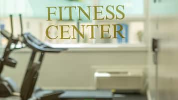 A fitness center with exercise equipment and a window in the background.
