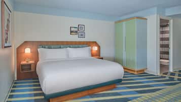 Una habitación de hotel con cama, lámparas de noche, un armario y piso alfombrado.
