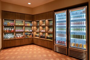 A corner of a room with wooden cabinets and shelves stocked with snacks and beverages.