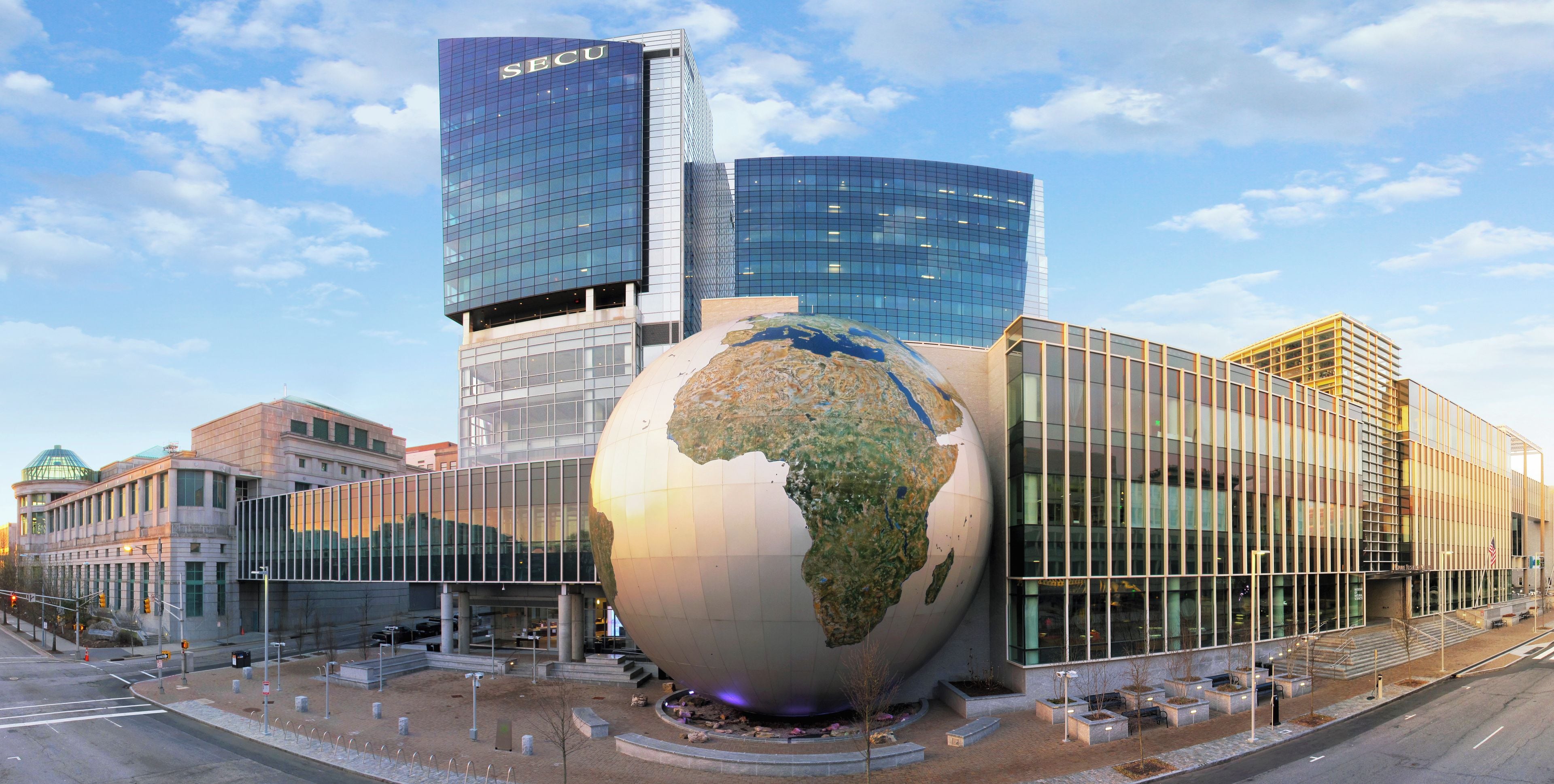 A modern building with a large glass globe sculpture in front.