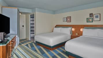 A hotel room with two beds, a television, a desk with a computer, and a bathroom visible through an open door.