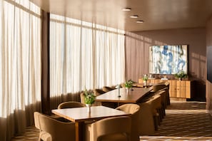 A hotel conference room with a long table, multiple chairs, a wooden cabinet, and a large abstract painting on the wall. - Hotel Indigo Raleigh Downtown by IHG (Raleigh)