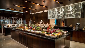 A modern kitchen with a central island filled with various food items and a decorative wall with abstract designs. - InterContinental Bahrain by IHG (Manama)