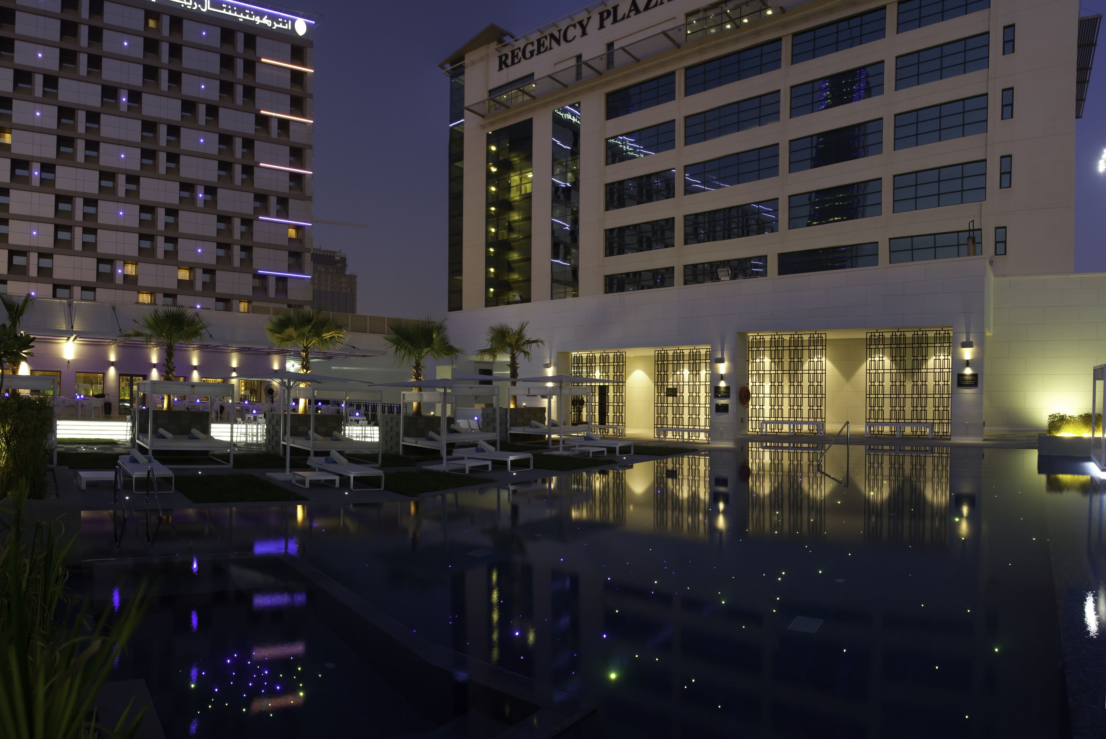 A hotel with a pool area, lounge chairs, and a reflection pool.