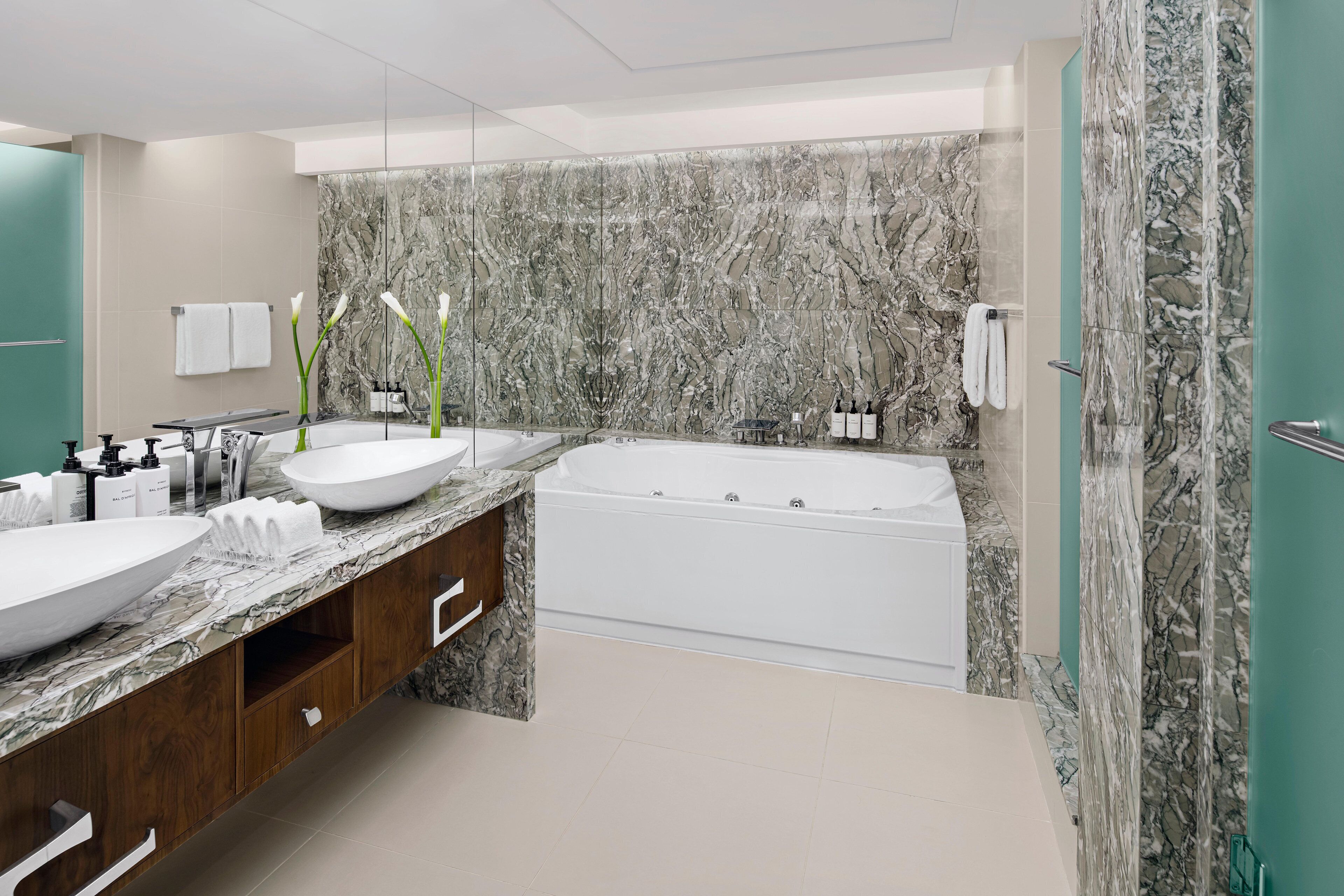 Une salle de bain moderne avec un grand lavabo en marbre, une baignoire et un meuble-lavabo doté de placards en bois.
