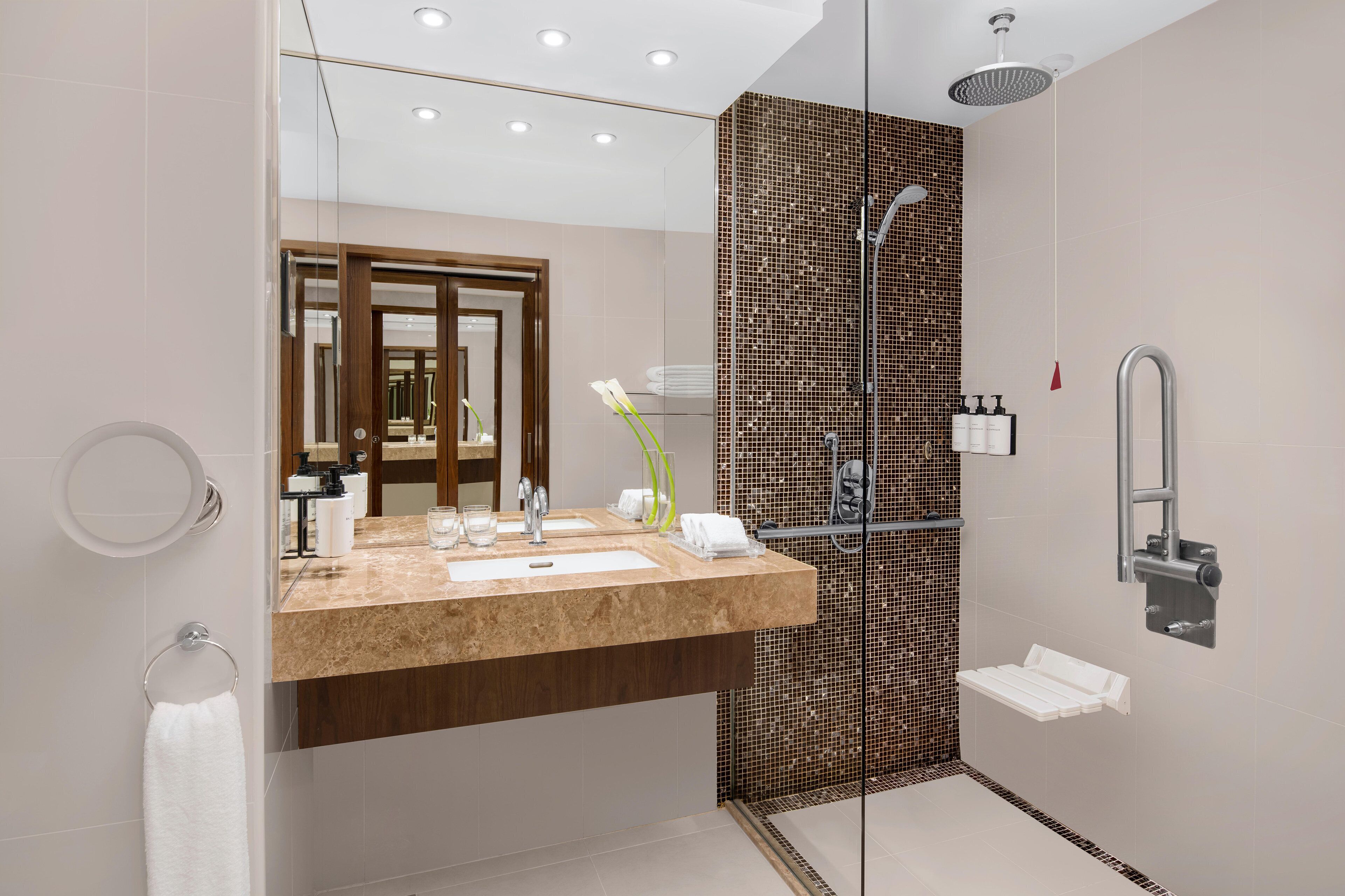 A modern bathroom with a glass-enclosed shower, a vanity with a mirror, and a towel rack.