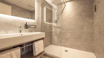 A modern bathroom with a glass-enclosed shower, a large mirror, and a white vanity.