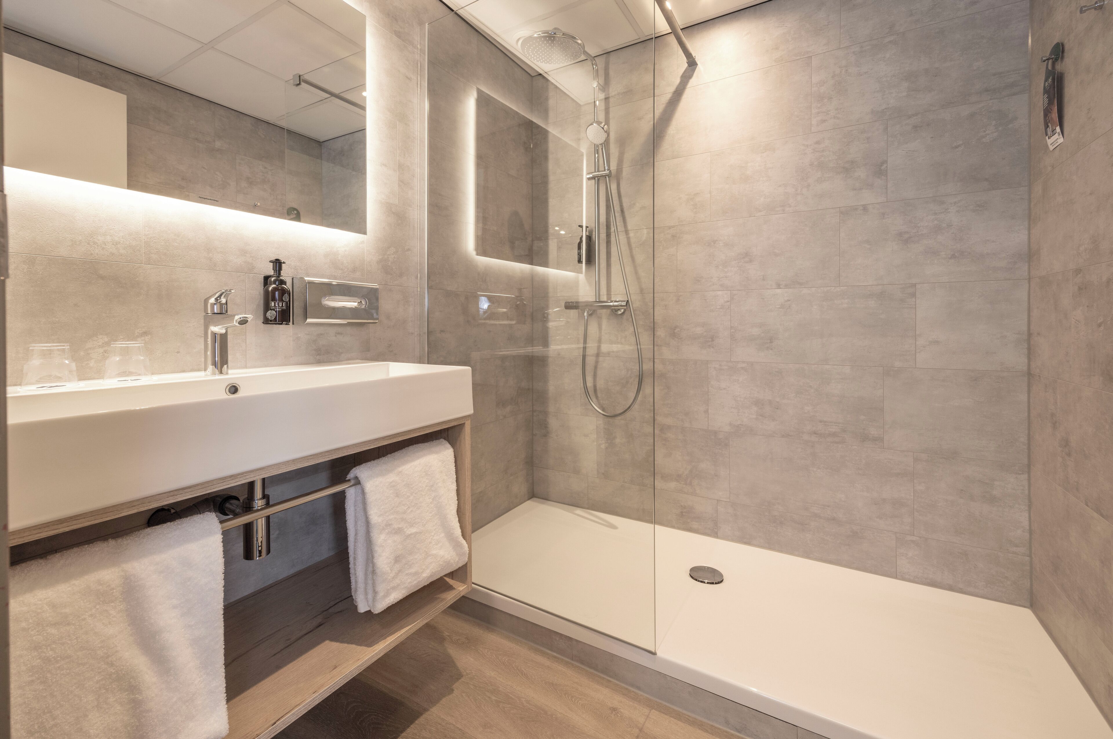 A modern bathroom with a glass-enclosed shower, a white sink, and a mirror.