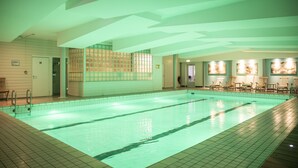 Una piscina interior con paredes de azulejos y techo con diseños geométricos.