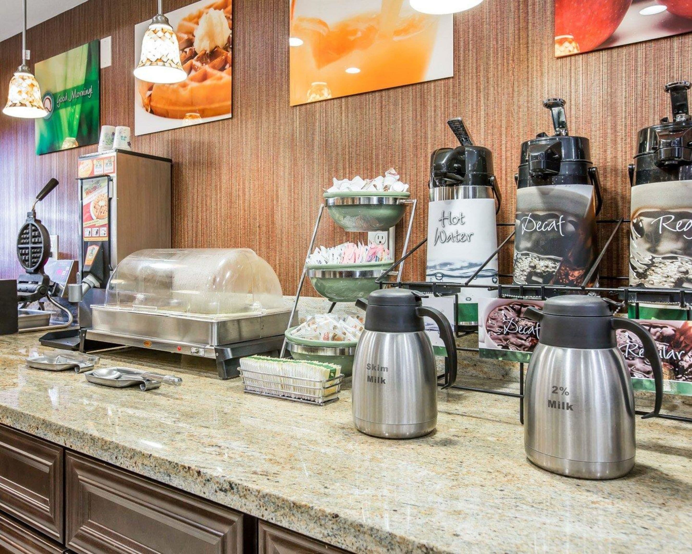 A buffet area with various food stations, including a waffle maker, a hot water station, and milk dispensers.
