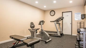 Centro de atividades físicas com equipamentos de cardio, aparelho de supino e halteres.
