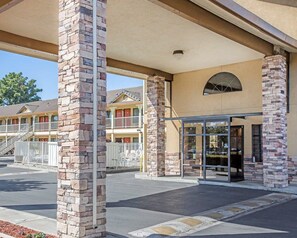 A motel with a stone facade, a covered entrance, and a parking lot. - Quality Inn & Suites Woodland - Sacramento Airport (Woodland)