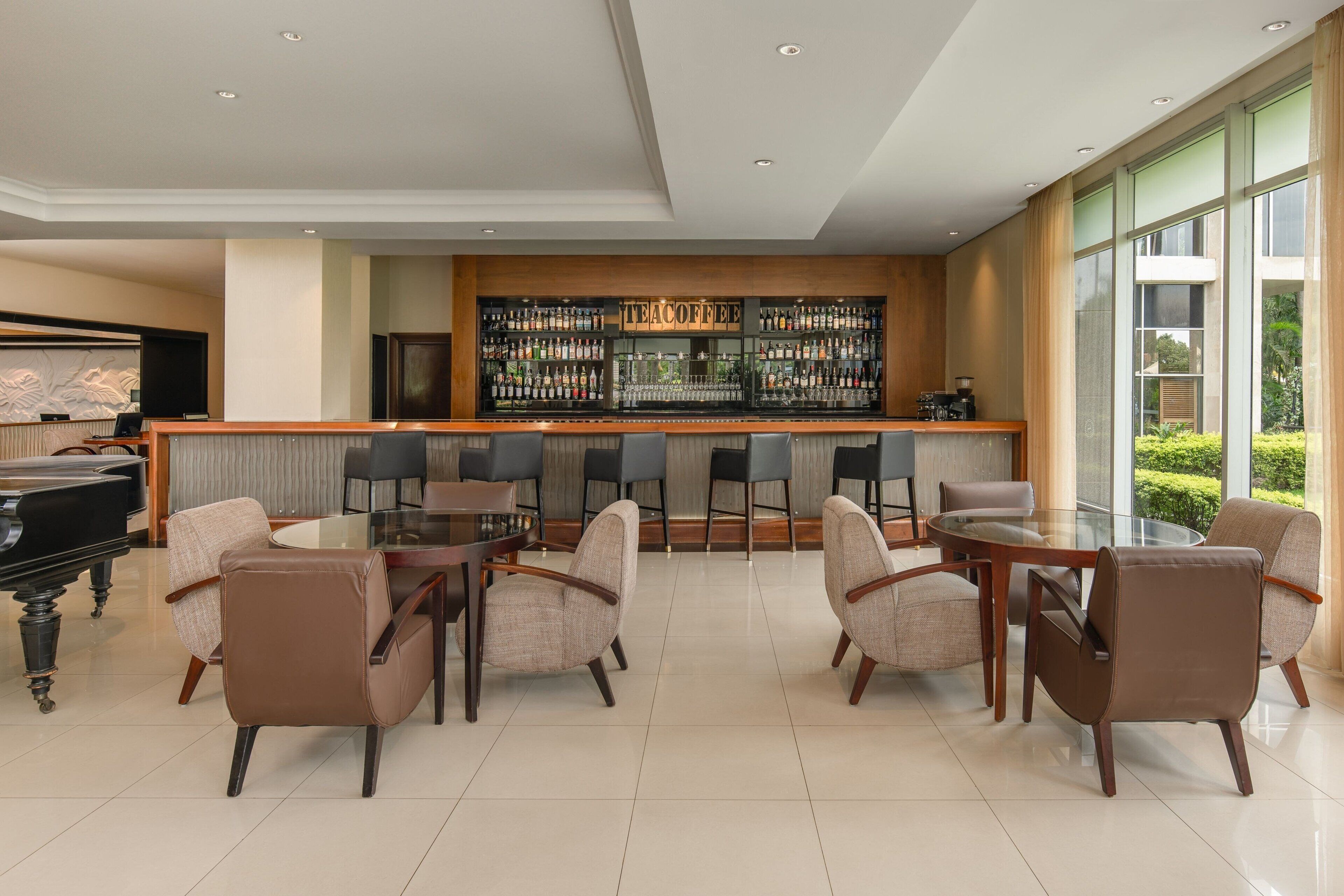 A modern bar area with a variety of liquor bottles, a piano, and comfortable seating.