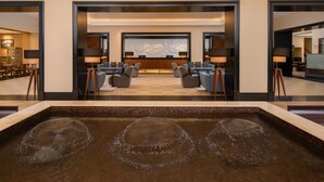A modern lobby with a central seating area, a large wall art piece, and a water feature. - Sheraton Kampala Hotel (Kampala)