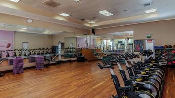Ein Fitnessraum mit Trainingsgeräten, Spiegeln und Holzboden.