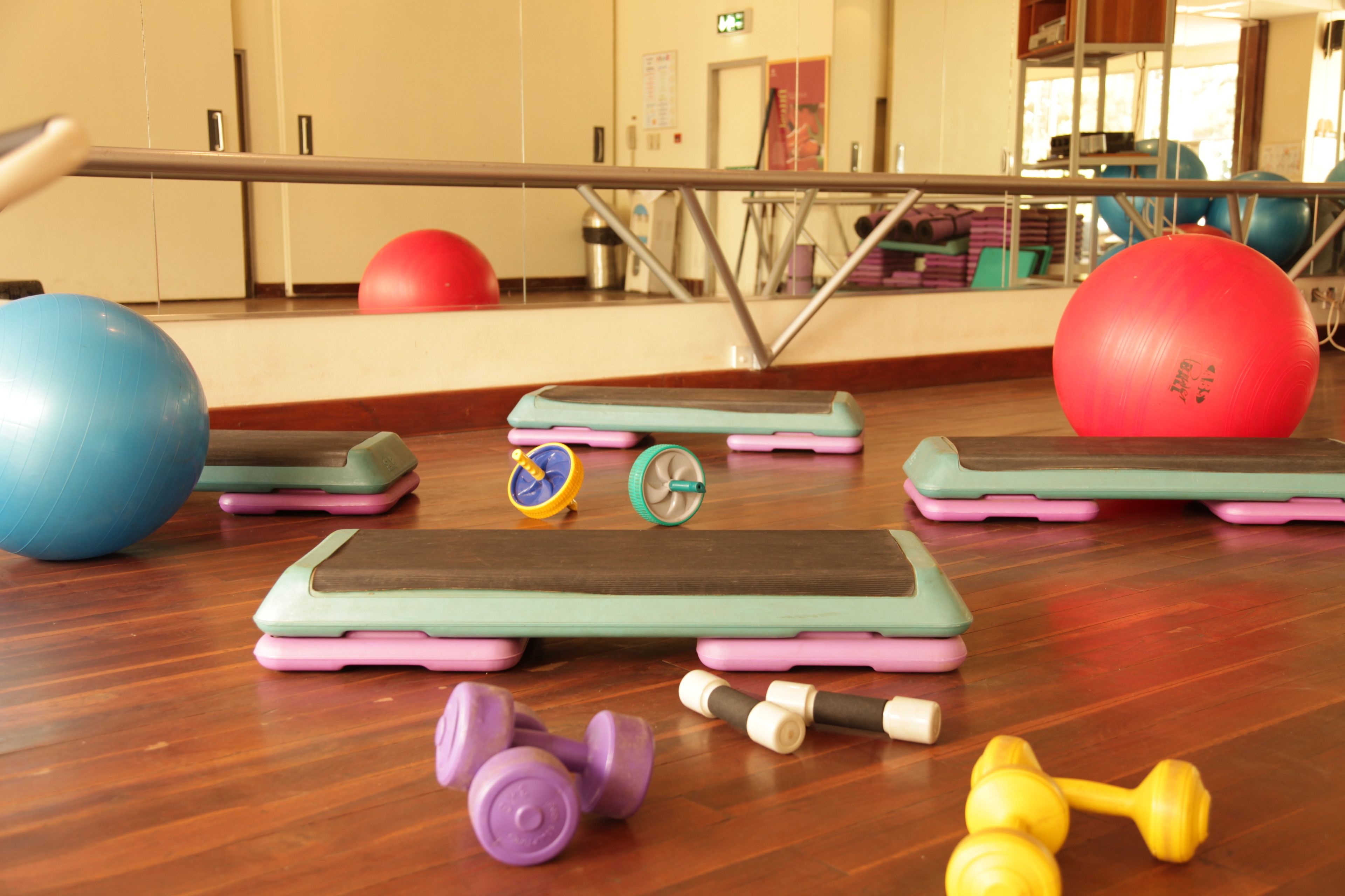 A gym with exercise equipment including balance boards, a mirror, and a wooden floor.