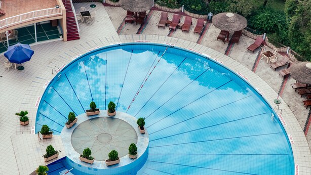 A large, circular swimming pool with a central island, surrounded by lounge chairs and umbrellas. - Sheraton Kampala Hotel (Kampala)