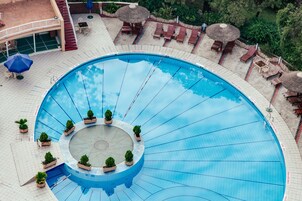 Una piscina al aire libre, sombrillas, sillones reclinables de piscina